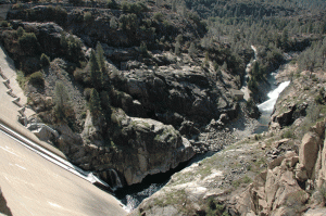 The view looking down from the dam to the Toulomne river as it continues on its way. The plume of spray is the water exiting from the generating tunnel after turning the turbines.